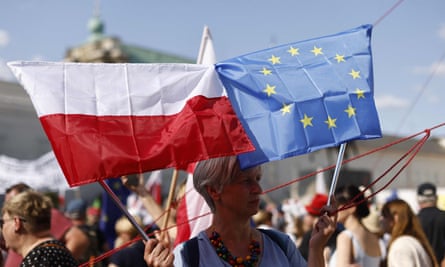 Kobieta trzyma polską i europejską flagę na antyrządowej demonstracji przed pałacem prezydenckim.