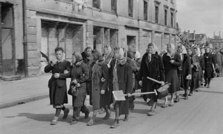 Women walk down a street in Warsaw carrying shovels