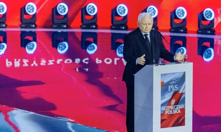 Jarosław Kaczyński speaking from a podium in front of a red backdrop