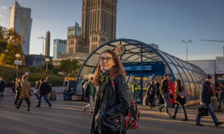 Woman stands in front of metro station with high-rise buildings behind