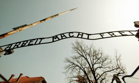 The Arbeit Macht Frei sign silhouetted against the sky.