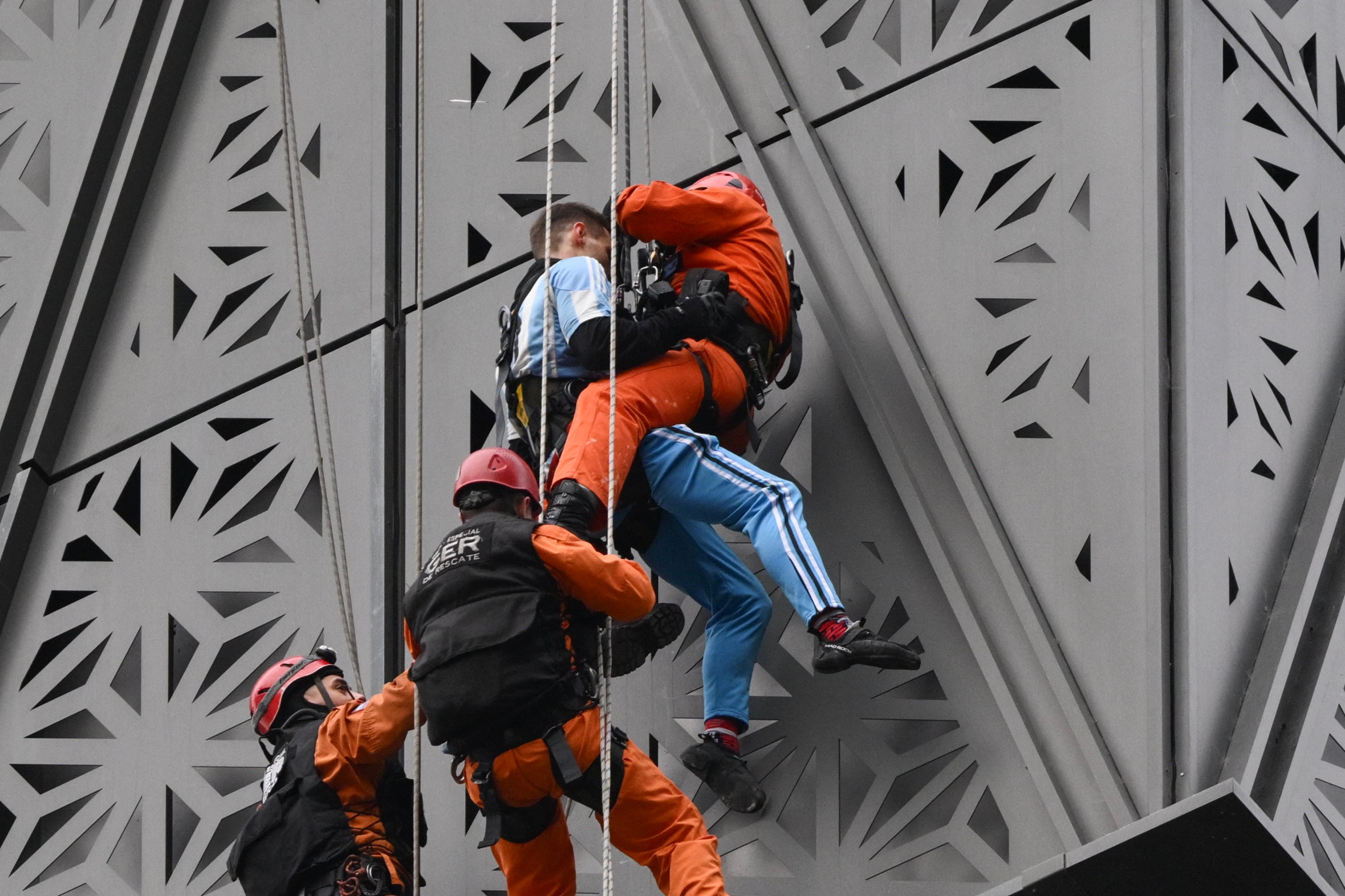 Firefighters intercept Polish climber Marcin Banot (2nd-R) as he climbed a building in Puerto Madero