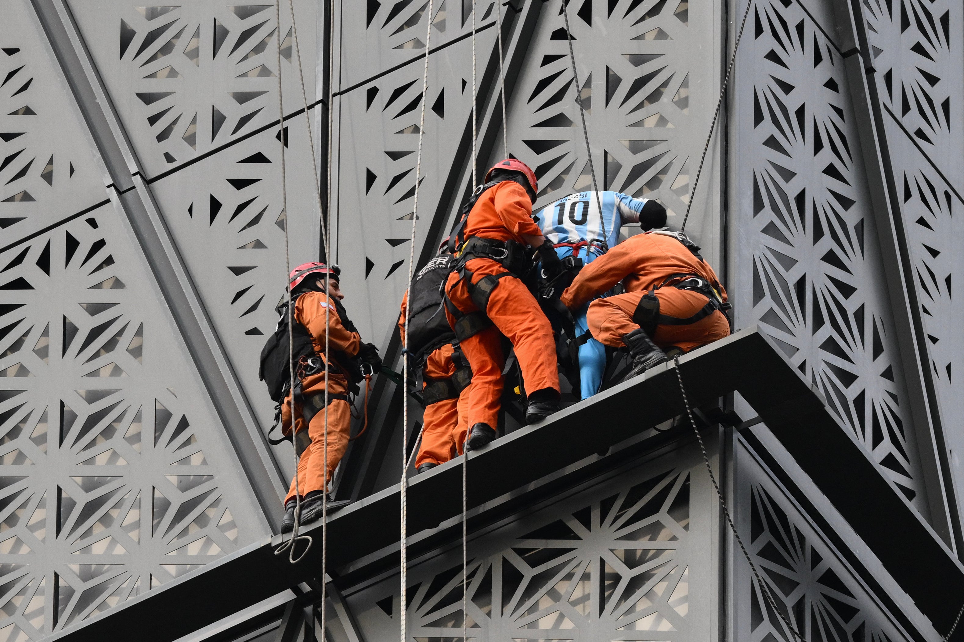 Firefighters intercept Polish climber Marcin Banot (2nd-R) as he climbed a building in Puerto Madero wearing an Argentina national football team jersey with Lionel Messi's number 10