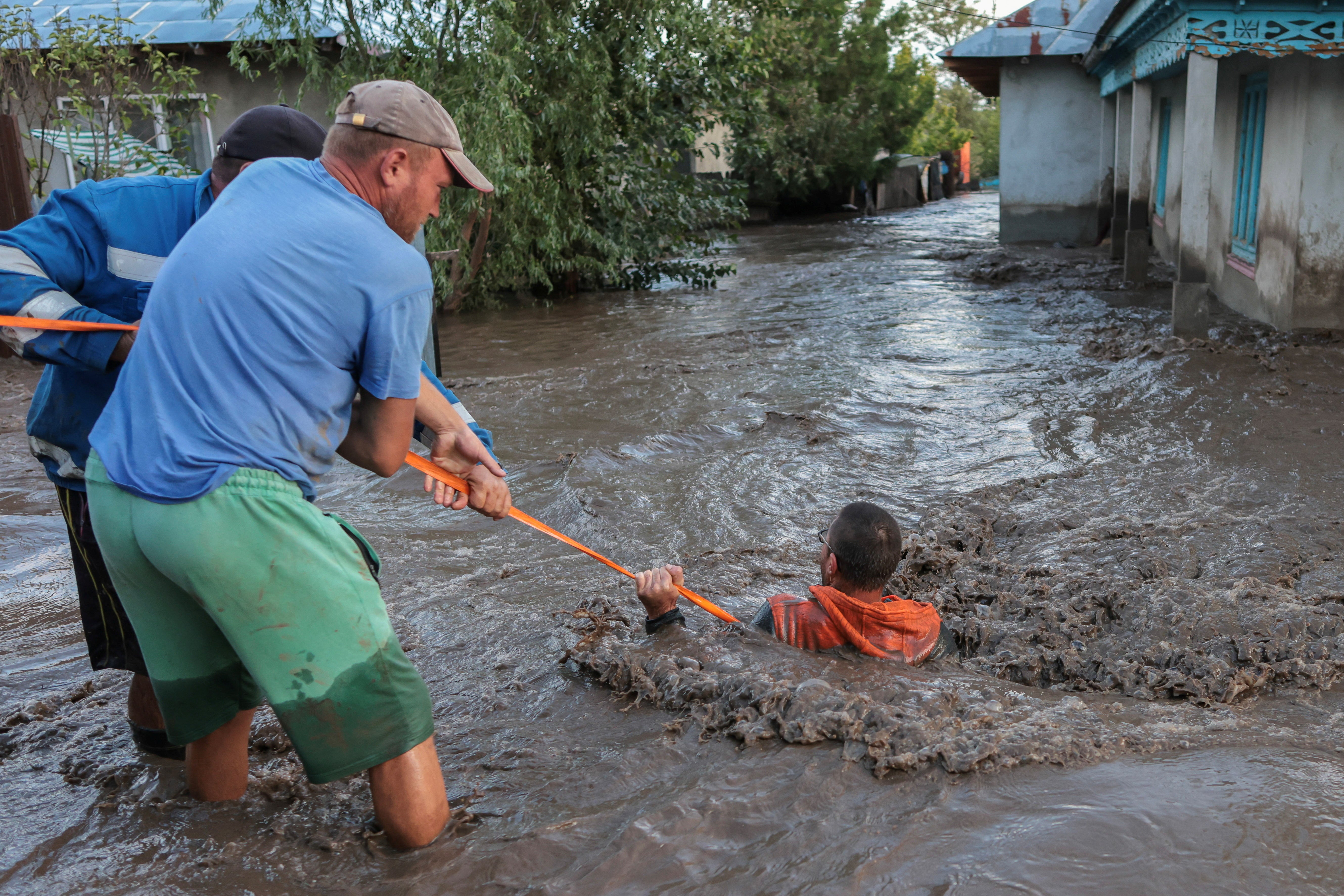 Locals and rescuers pull a man through flood water, after heavy rain triggered flooding in Slobozia Conachi, Galati country, Romania