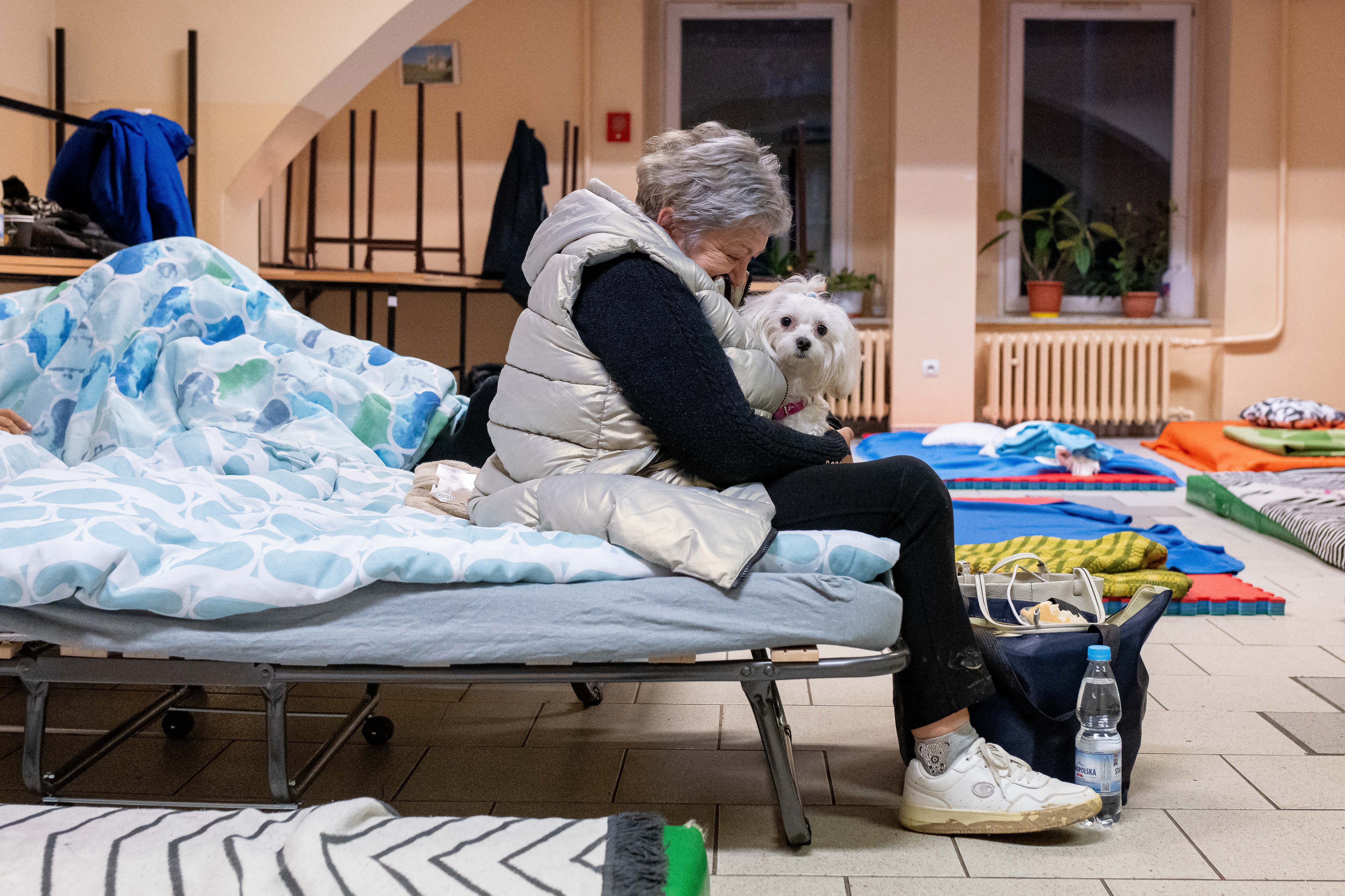 An evacuated local resident rests as she takes shelter with her dog at a school in Nysa, southern Poland